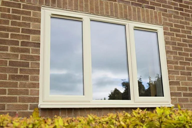 Cream uPVC casement window set in a brick wall