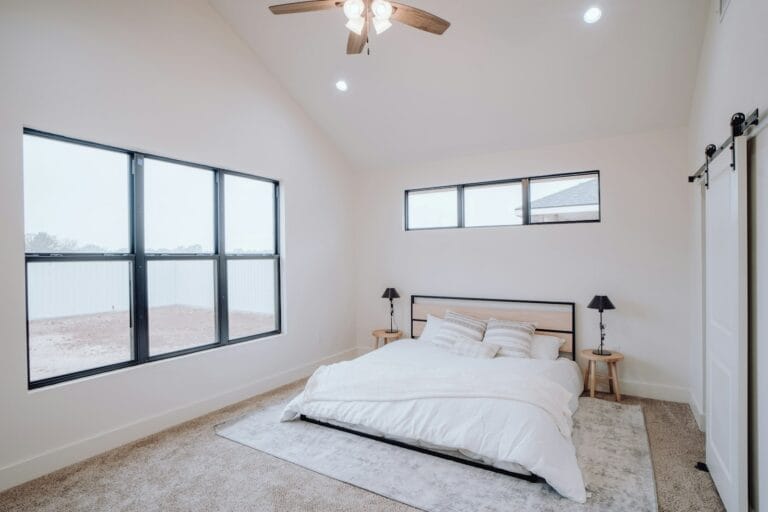 Bright bedroom with a large three-pane window beside the bed and a row of narrow high windows above the headboard